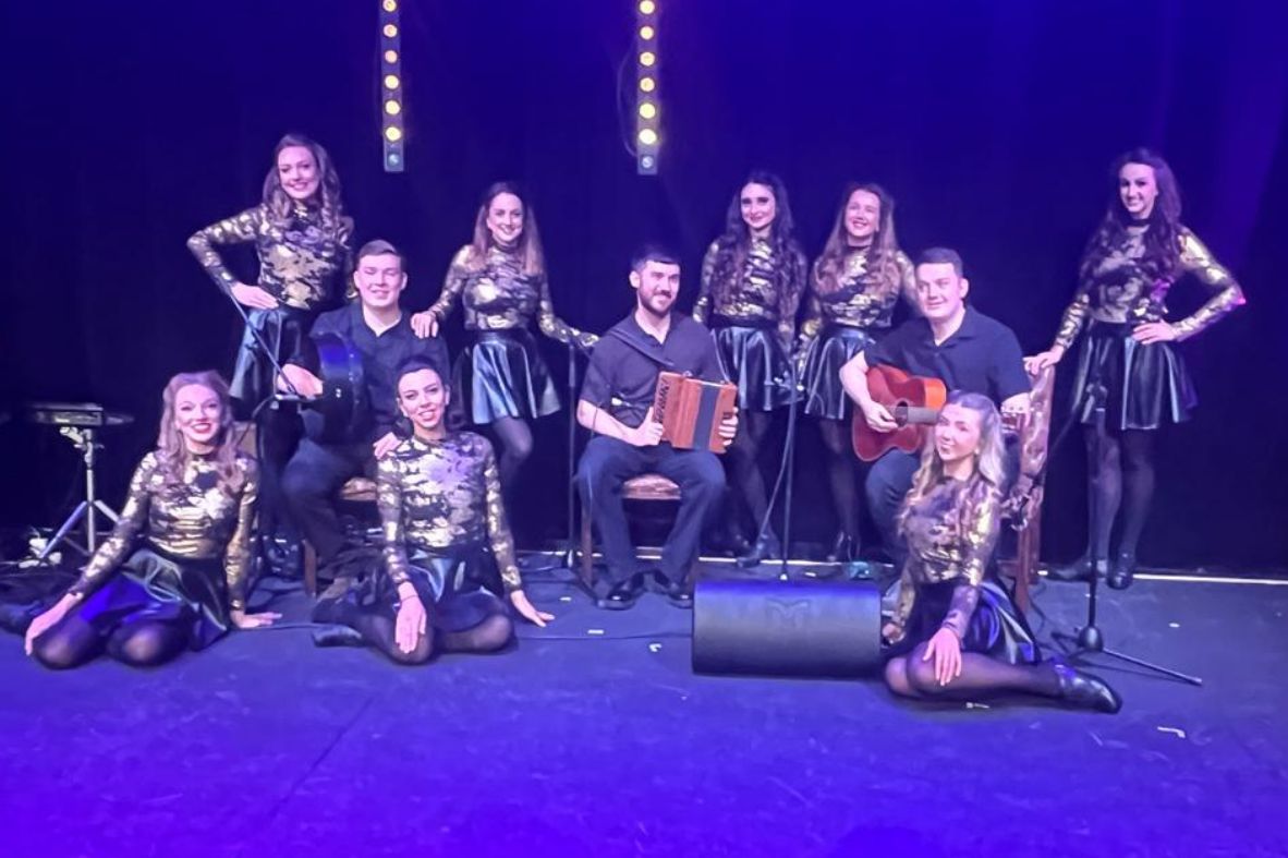Elite Irish Dance performers with live Irish musicians during a stage show